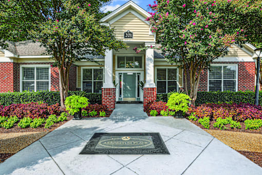 A brick building with a porch and a tree in front.