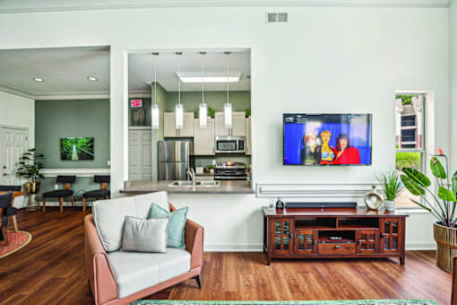 A living room with a grey couch and a television on the wall.