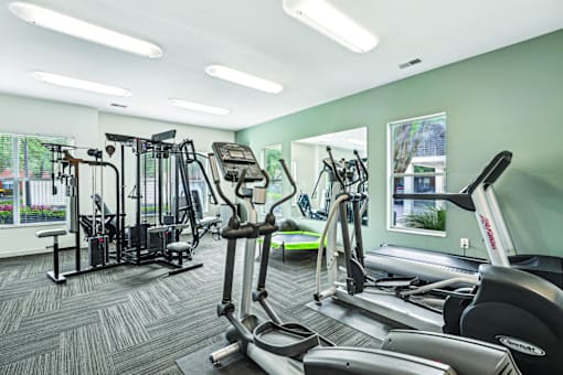 A gym with a variety of equipment including treadmills, weights, and exercise machines.