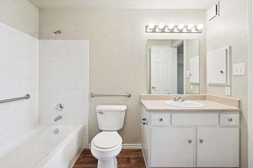 A white toilet sits in a bathroom next to a white bathtub.