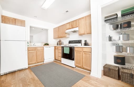 Virtually staged kitchen with grey rug, wood floors, and white appliances. Virtually staged pantry inside kitchen