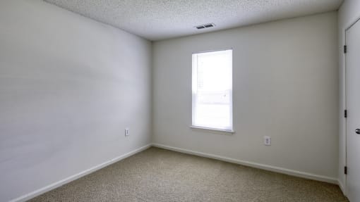 a bedroom with white walls and a window
