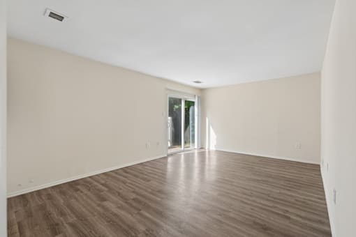 A room with wooden flooring and a sliding glass door.