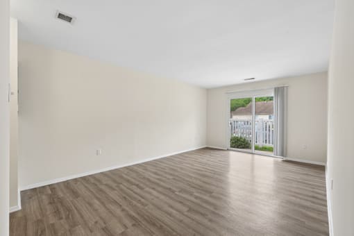 Empty room with wooden flooring and a window.