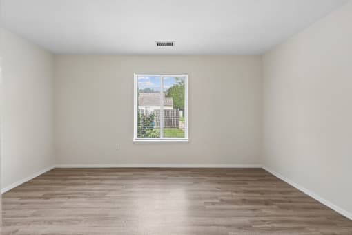Empty room with a window showing a view of a building and trees.