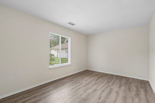 A room with a window and wooden flooring.