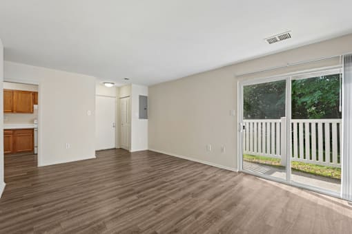 A room with wooden flooring and a sliding glass door leading to a balcony.
