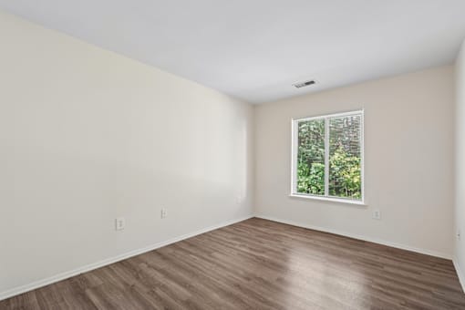 Empty room with wooden flooring and a window.