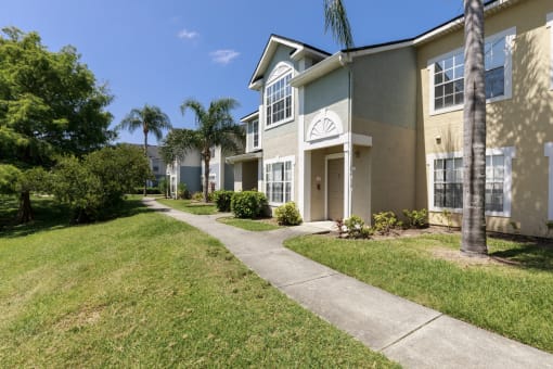 Sidewalk Surrounded by Grass with Apartment Building Exterior and Trees