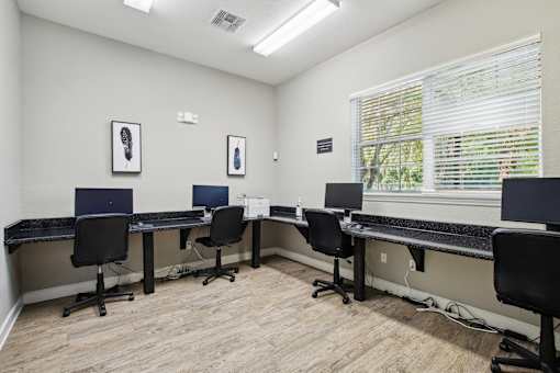 A room with a desk and chairs with a laptop on it.