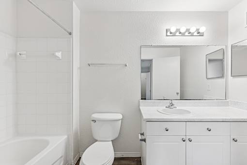 A white bathroom with a toilet, sink, and bathtub.
