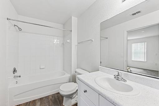 A white bathroom with a toilet, sink, and bathtub.