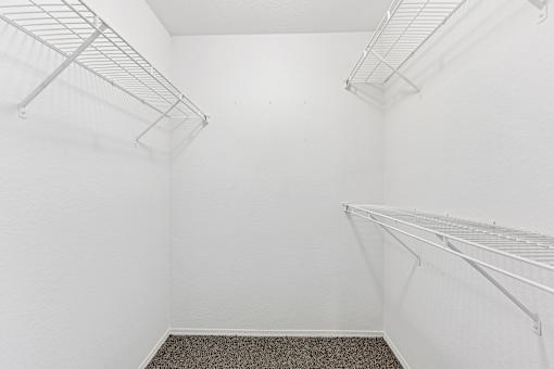 Empty white room with metal shelves and carpeted floor.