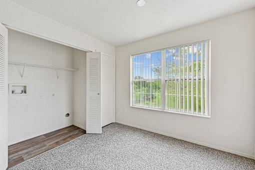 A room with a sliding door and a window with a view of a fence and trees outside.