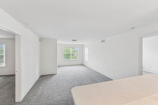 A spacious room with a carpeted floor and a large window.