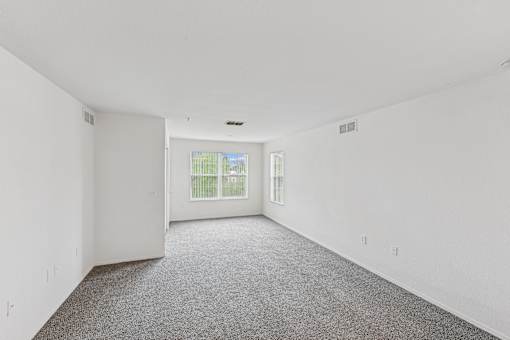 A large empty room with a carpeted floor and white walls.
