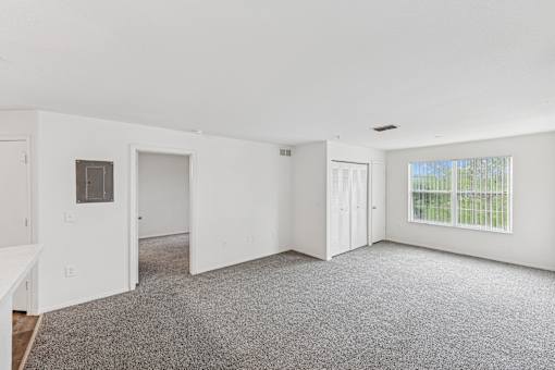 A spacious room with white walls and carpeted floor.