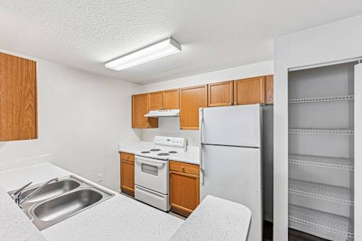 A kitchen with a white fridge, stove, and sink.