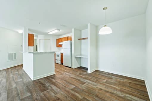 A kitchen with white walls and wooden floors.