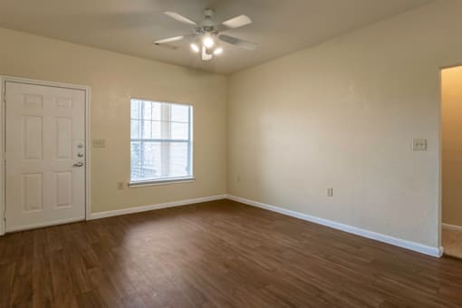 an empty living room with wood floors and a ceiling fan