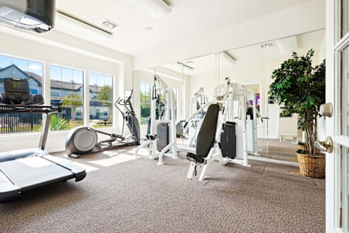 a gym with cardio equipment and windows in a building