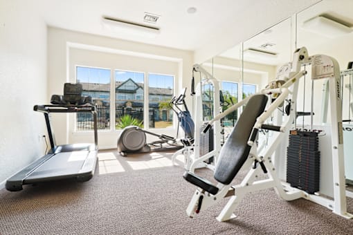 a gym with weights and cardio equipment and a window