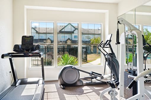 a home gym with exercise equipment overlooking a patio