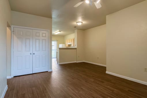 an empty living room and kitchen with wood flooring and a white door