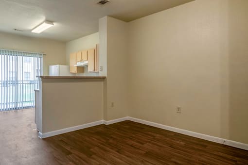 an empty living room with a kitchen and a window