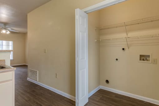 an empty living room with a door to a closet and a hallway to a kitchen