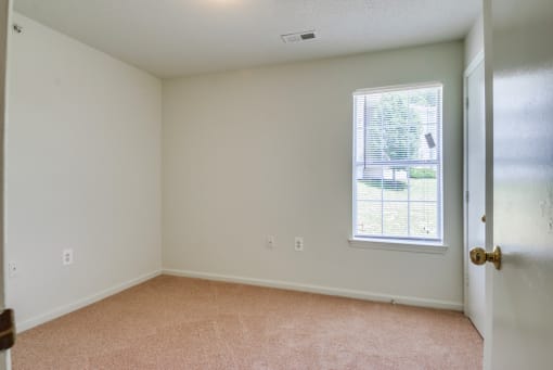 a bedroom with white walls and carpet