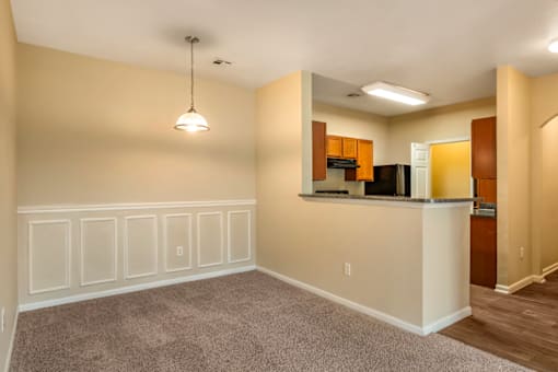 a bedroom with white wainscoting and a kitchen in the background
