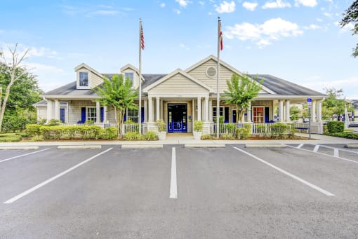 Clubhouse front view with flag poles, parking lot and native landscaping