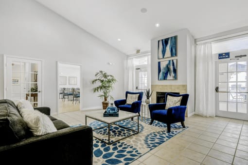 Clubhouse interior featuring couch with pillows, fabric chairs with pillows, fireplace, coffee table with decor and entrance into dining area