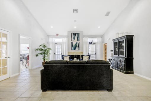 Clubhouse interior facing back back of couch, fireplace, fabric chairs with cabinet and decor
