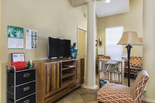 Clubhouse Seating Area in Front of Entertainment Center with TV Next to Bookshelf