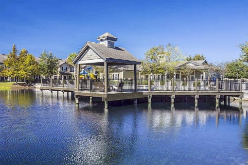Swimming pool deck with covered seating area over the lake.