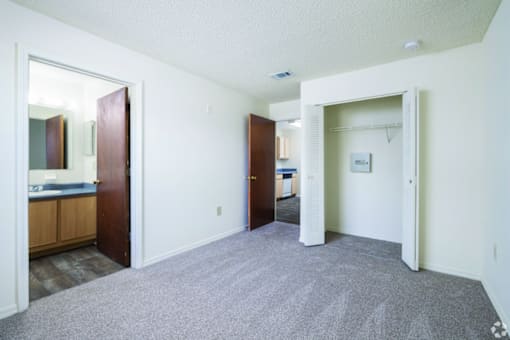 A room with a carpeted floor and two open doors.
