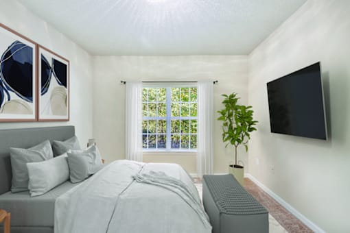 A bedroom with a bed, a window with blinds, a plant, and a television mounted on the wall.