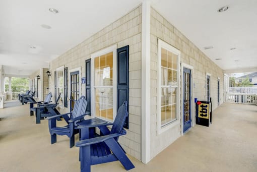 Corner view of clubhouse porch with recessed lighting featuring blue Adirondack chairs