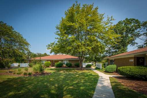 an apartment with a sidewalk and trees in front of it