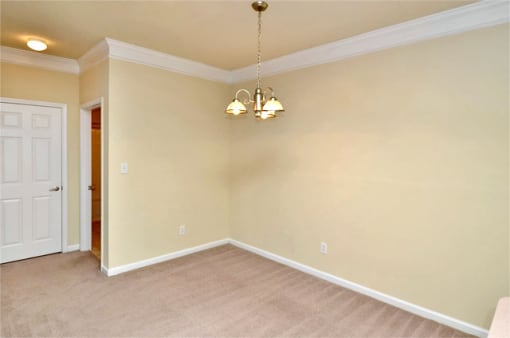 Carpeted dining area with beige walls and ceilings. The entry door is in the background.