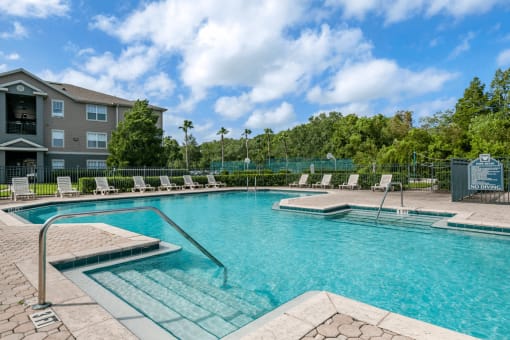 Swimming pool with lounge seating surrounded by native landscaping