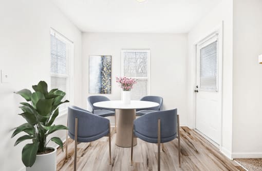 Virtually staged dining room with wood table and grey accent chairs. Hardwood flooring and natural lights with windows and door leading to outside.