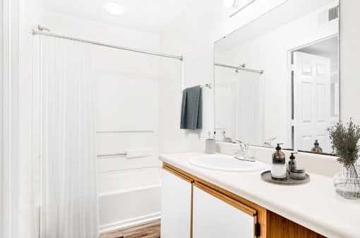 Virtually staged; Bathroom with wood cabinets, white countertops, and chrome finish outs. Bathroom accessories and grey towel