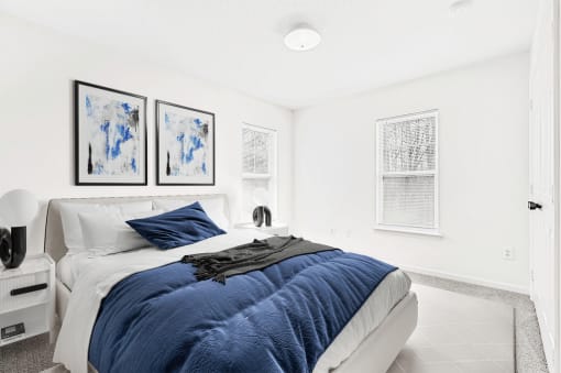 Virtually staged; Carpeted bedroom with two windows, bed and night stands with blue/ grey accents and wall art