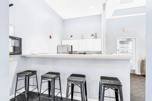 Clubroom kitchen. Bar area with four bar stools and a hightop counter.