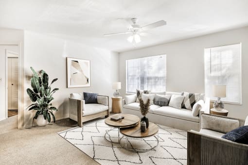 Virtually staged living room with couch, tv, ceiling fan, large windows, and coffee table