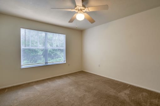 Living room with carpet flooring, large window for natural lighting, and multi speed ceiling fan