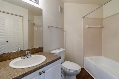 Bathroom with large mirror, vanity lighting, and tiled shower